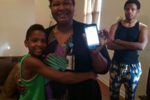 When her son William started taking public transportation to school, Lashunda Dean downloaded a tracking app on her cellphone. She shows off the app while her older son and the family cockatiel look on. Credit: Mallory Falk / WWNO